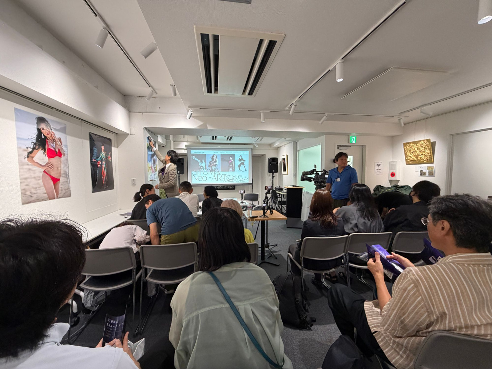 開演前の会場。スクリーンには「STOMA Néo-ART Talk Event」の文字、壁には小菅キャスリン綾子さんの写真パネルが並んでいました