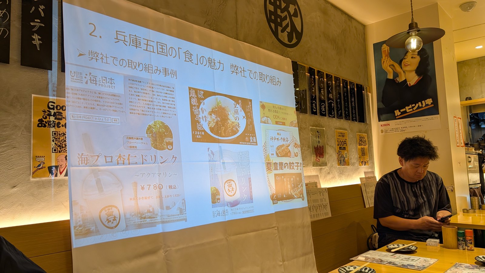兵庫五国の食の魅力 弊社での取り組みと題したスライド。コラボドリンク、麻辣油そば、餃子などの事例